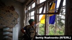 Украин аскери Алексей Довбуша орус армиясынан жакында эле бошотулган Благодатное айылындагы Маданият үйүндө илинип турган украин желегин оңдоп жатат. 17-июнь, 2023-жыл. Донецк облусу, Украина. "Эркин Европа/Азаттык радиосу"/Сергей Нужненко.