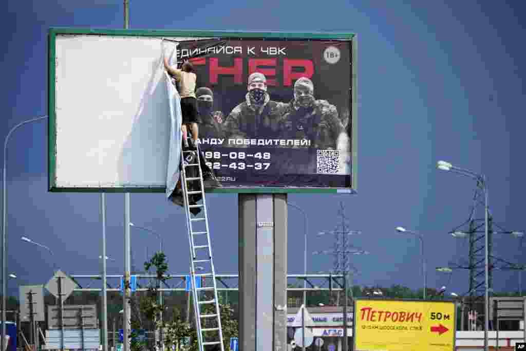 Мужчина снимает рекламный билборд о вербовке в группу «Вагнер», 24 июня у шоссе на окраине Санкт-Петербурга