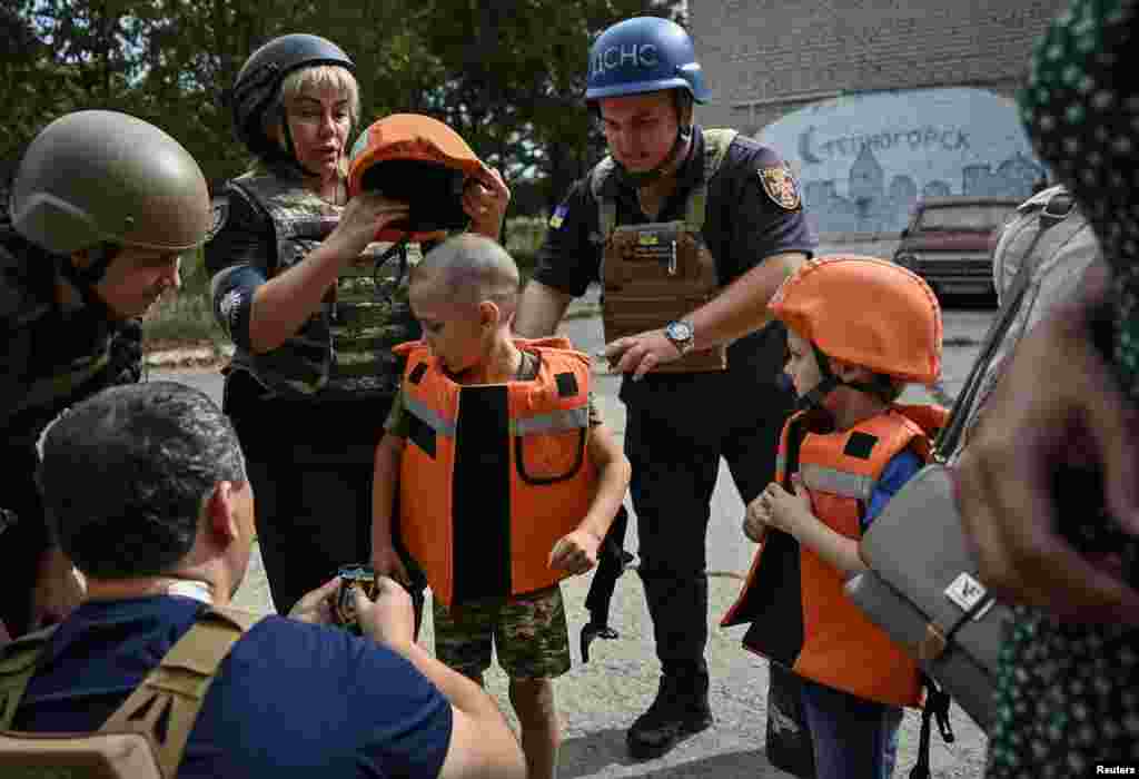 Polițiștii echipează copiii cu veste antiglonț și căști de protecție înainte să fie evacuați dintr-un sat din regiunea Zaporojie, Ucraina, 31 august 2023.