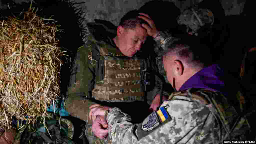 Военный капеллан Александр благословляет украинского солдата в Харьковской области на северо-востоке страны, 24 апреля 2022 года