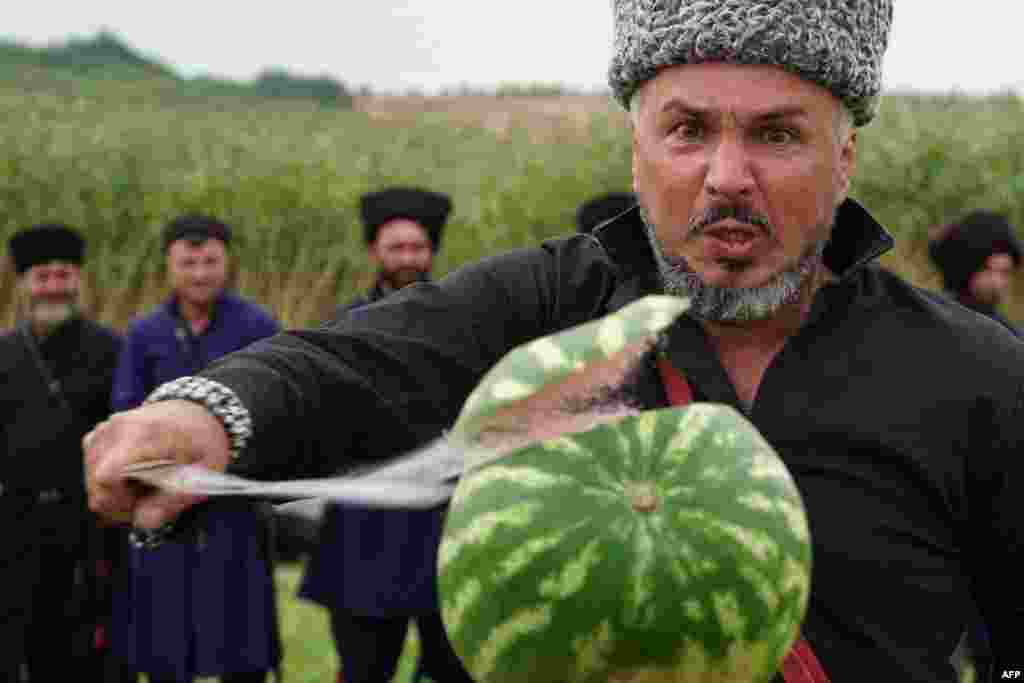 Un cazac taie un pepene verde, în timpul unei competiții de tăiere a pepenilor verzi cu sabia, din regiunea Rostov, Rusia, 27 august 2023.