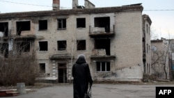 Жінка проходить повз зруйновану будівлю у Красногорівці Донецької області, 22 лютого 2022 року. Фото ілюстративне 