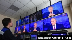 Сотрудник телеканала включает российский государственный телеканал, на котором показывают выступление Путина. Архивное фото