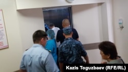 В глубине лифта кардиологического центра в Алматы — один из конвойных, ближе (в белой майке) фигурант дела о «пропаганде терроризма» Жулдызбек Таурбеков, еще ближе — человек в штатском, руководивший действиями конвойных, еще ближе — еще один конвойный. Алматы, 6 июля 2019 года.