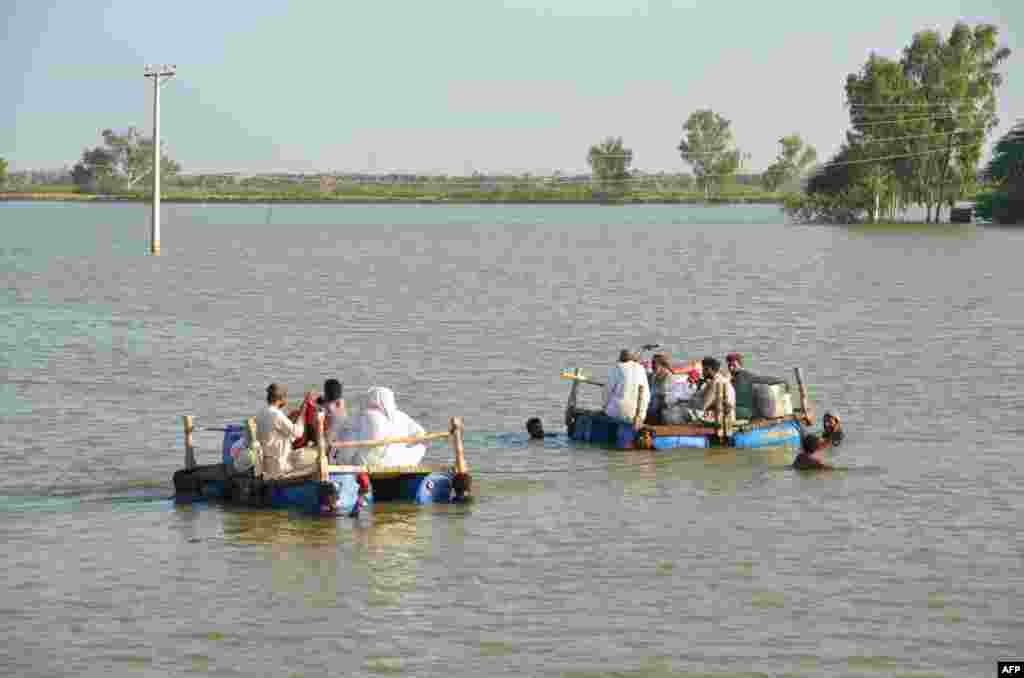 People on makeshift rafts are pulled across floodwaters in the Jaffarabad district on September 18. The World Health Organization says a surge in sickness as a result of the flooding has the potential to become a "second disaster." 