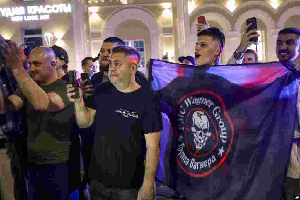 Люди аплодируют и машут флагом ЧВК «Вагнер» возле военного штаба в Ростове-на-Дону. Кремль заявил, что Александр Лукашенко из Беларуси помог в заключении сделки с Пригожиным. Пресс-секретарь Кремля Дмитрий Песков сообщил, что Путин и Лукашенко гарантировали безопасность владельца ЧВК 