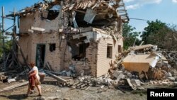 Lokalna stanovnica nosi stvari iz ruševina svoje kuće, koja je uništena u ruskom raketnom napadu na Kijevsku oblast 27. augusta.