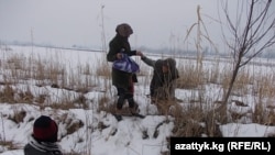 Чек арадагы көмүскө жолдон өтүп жаткан жарандар.