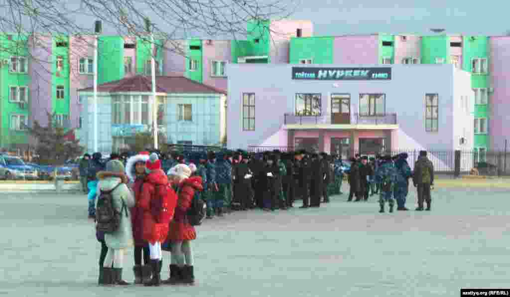Жаңаөзеннің орталық алаңында тұрған балалар мен полиция қызметкерлері.