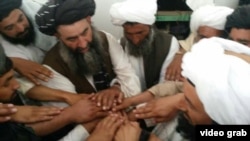 تصویری از هبت‌الله آخوندزاده، رهبر طالبان افغانستان (با دستار سیاه در مرکز عکس)؛ این تصویر بخشی از ویدئویی ست که به دست گزارشگر رادیو اروپای آزاد در پیشاور پاکستان رسید و «بیعت» مقام‌های ارشد طالبان را با رهبر جدیدشان نشان می‌دهد.