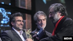مسعود کیمیایی (راست) جایزه خود را از معاون سینمایی وزارت ارشاد می‌گیرد