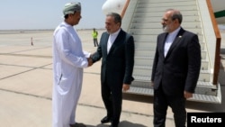 Iranian Foreign Minister Abbas Araqhchi (center) is welcomed by an unidentified Omani official upon his arrival in Muscat, Oman, for nuclear talks with the United States on May 11.