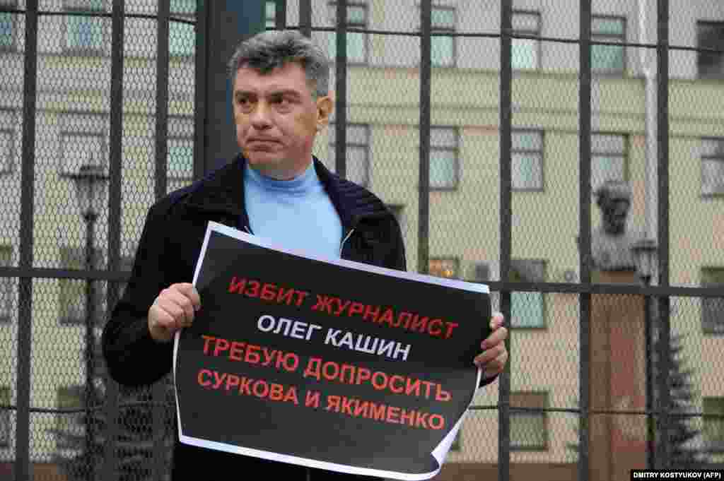Борис Немцов держит плакат с требованием начать расследование по делу избиения оппозиционного журналиста Олега Кашина. 