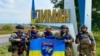 Ukrán katonák a felszabadított Limant jelző táblánál 2022. október 2-án