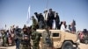 FILE: Afghan Taliban militants and residents stand on a armored Humvee vehicle of the Afghan National Army (ANA) as they celebrate a ceasefire on the third day of Eid in Maiwand district of Kandahar province on June 17.