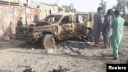 Residents look at an Army vehicle destroyed in fighting between Afghan security forces and Taliban in Farah city on May 16.