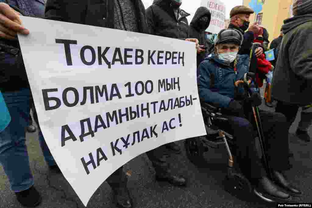 Мужчина в инвалидном кресле на митинге в Алматы. Надпись на плакате призывает президента Казахстана Касым-Жомарта Токаева услышать требования 100 тысяч человек. В августе инициативная группа по созданию Демократической партии во главе с Жанболатом Мамаем заявила, что в администрацию президента Токаева было передано «около 100 тысяч заявлений» с призывом объявить кредитную амнистию.