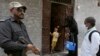 A police officer stands guard while a health-care worker administers a polio vaccine to a child in Karachi, Pakistan, in June. (file photo)