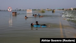 Djeca se igraju u poplavnoj vodi na glavnom autoputu u Sehwanu, Pakistan, 15. septembar 2022.