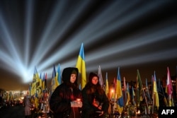 Символическая иллюминация под названием «Лучи памяти» над могилами украинских солдат, погибших в войне с Россией, во время посещения людьми Лычаковского военного кладбища во Львове 23 февраля 2025 года, накануне третьей годовщины войны с Россией