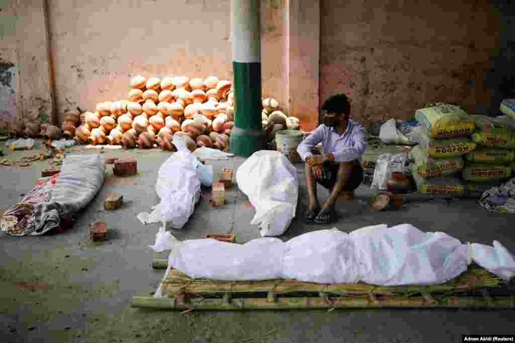 Ky person në Nju Delhi qëndron pranë disa trupave të pajetë, që janë sjellë në një krematorium më 26 prill. 