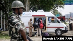 A member of India's security forces stands guard as police search a van on the Jammu-Srinagar highway at Nagrota on August 2.