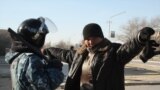Сотрудник полиции проверяет мужчину в городе Жанаозен Мангистауской области, 19 декабря 2011 года. 