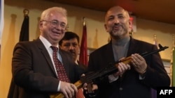 Кабулдагы орус элчиси Александр Мантыцкий Ооганстандын улуттук коопсуздук боюнча кеңешчиси Ханиф Атмарга АК-47 автоматын тапшырууда, 24-февраль, 2016-жыл. 