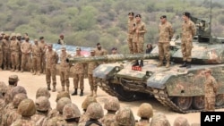 This handout photograph taken on May 1, 2025, and released by the Pakistan's Inter Service Public Relation (ISPR) shows Pakistan's Army Chief General Syed Asim Munir (Top 3R) standing on a tank and speaking with army troops.