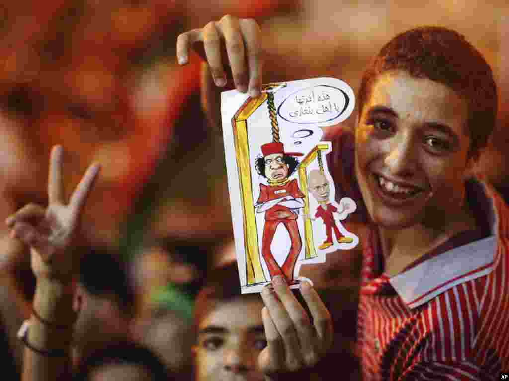 یک نوجوان در طرابلس کاریکاتوری از معمر قذافی و پسرش را در دست دارد- ۳۱ مردادماه ۱۳۹۰