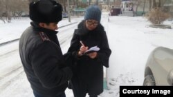 Полицейский вручает репортеру Азаттыка Сание Тойкен повестку на допрос в качестве свидетеля в ДВД Мангистауской области. Актау, 17 февраля 2017 года.