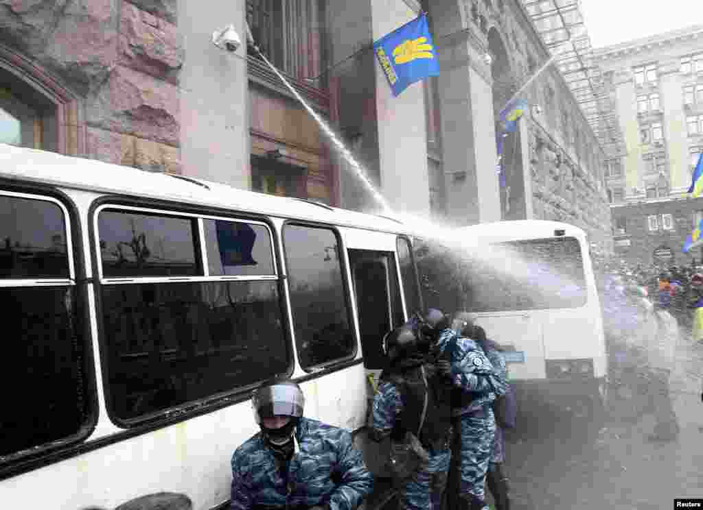Мітингувальники Євромайдану обливають з пожежного шлангу бійців спецпідрозділу «Беркут», щоб завадити штурмові КМДА, Київ, 11 грудня 2013 року