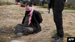A suspected Islamic State militant is guarded by a soldier from the Iraqi special forces at a temporary base in the Samah neighborhood of Mosul on November 16.