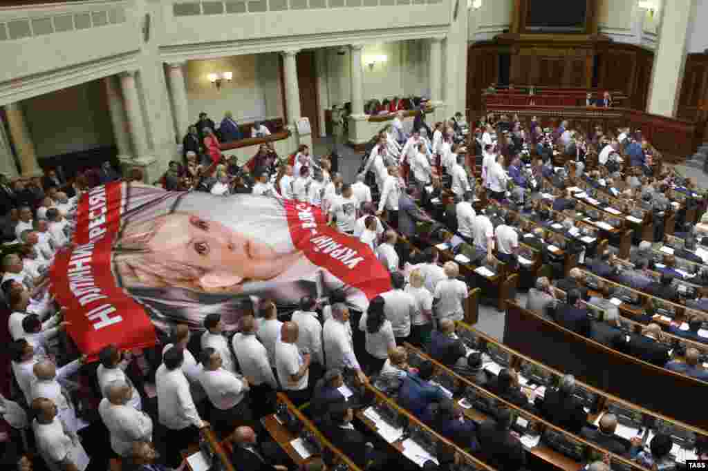 Жогорку Раданын оппозициячыл депутаттары Тимошенкого колдоо иретинде парламентте анын плакатын жайып жатышат. 2013-жылдын май айы. 