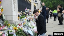 Un tânăr se reculege în fața Palatului Buckingham după ce s-a anunțat decesul Reginei Elisabeta a II-a, Londra, 9 septembrie 2022