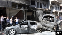 People look at burned-out car bombs after an attack that killed at least 10 people and wounded 62 in the Jaramanah suburb in southeast Damascus on July 25.