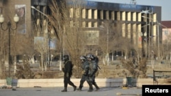 Полицейский патруль на фоне поврежденных зданий. Жанаозен, 19 декабря 2011 года.