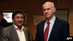 Gresiýanyň premýer-ministri George Papandreou (sagda) Liwiýanyň daşary işler ministriniň orunbasary Abdelati al-Obeýdi bilen duşuşýar, Afiny, 2011-njy ýylyň 3-nji apreli.