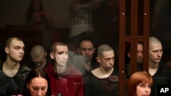 Captured members of Ukraine's Azov Battalion sit inside a defendants' glass cage during a hearing at a court in Rostov-on-Don, Russia.